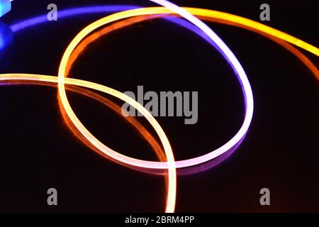 Gelbes und blaues Lichtkabel, ein Lichtleiterkabel mit unterschiedlicher Lichtdurchlässigkeit, unterschiedlichem Lichtspektrum und Lichteffekten, das sich in einem chaotischen Zustand befindet. Stockfoto
