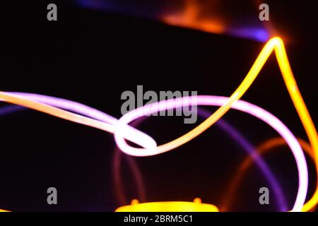 Gelbes und blaues Lichtkabel, ein Lichtleiterkabel mit unterschiedlicher Lichtdurchlässigkeit, unterschiedlichem Lichtspektrum und Lichteffekten, das sich in einem chaotischen Zustand befindet. Stockfoto