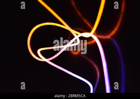 Gelbes und blaues Lichtkabel, ein Lichtleiterkabel mit unterschiedlicher Lichtdurchlässigkeit, unterschiedlichem Lichtspektrum und Lichteffekten, das sich in einem chaotischen Zustand befindet. Stockfoto