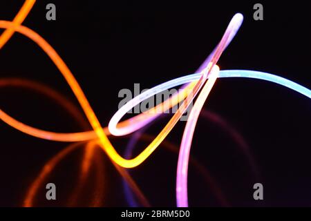Gelbes und blaues Lichtkabel, ein Lichtleiterkabel mit unterschiedlicher Lichtdurchlässigkeit, unterschiedlichem Lichtspektrum und Lichteffekten, das sich in einem chaotischen Zustand befindet. Stockfoto
