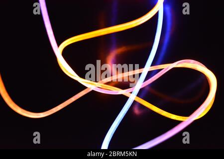 Gelbes und blaues Lichtkabel, ein Lichtleiterkabel mit unterschiedlicher Lichtdurchlässigkeit, unterschiedlichem Lichtspektrum und Lichteffekten, das sich in einem chaotischen Zustand befindet. Stockfoto
