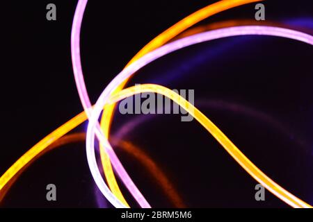 Gelbes und blaues Lichtkabel, ein Lichtleiterkabel mit unterschiedlicher Lichtdurchlässigkeit, unterschiedlichem Lichtspektrum und Lichteffekten, das sich in einem chaotischen Zustand befindet. Stockfoto