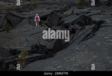 Eine Frau steht auf der geknackten und in Lava gefallenen Lava des Kilauea Iki Kraters, Hawaii Volcanoes National Park, Hawai'i, USA Stockfoto