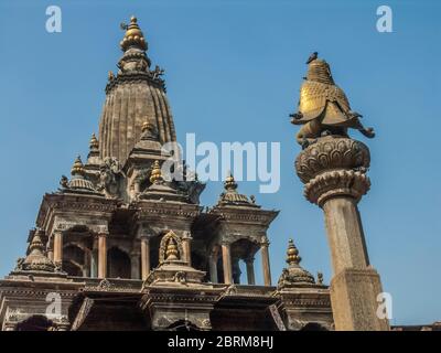 Nepal, Kathmandu. Bunte Straßenszenen auf dem mittelalterlichen Durbar-Platz in der antiken Stadt Patan mit Blick auf die mythische Vogelmann Garuda-Säule und den Krishna Mandir-Tempel, der von König Siddhirarsingh Malla im 17. Jahrhundert erbaut wurde Stockfoto