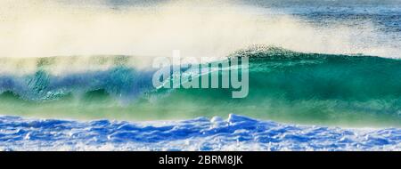 Ultrabreite Front der rollenden Welle, die bei Sonnenaufgang zum sandigen Nordstrand von Sydney rauscht. Stockfoto