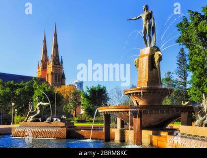 Türme und Türme der gotischen Kathedrale in Sydney nahe dem Hyde Park und erfrischender Wasserbrunnen an einem sonnigen Tag. Stockfoto