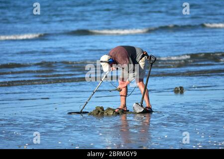 Schatzsucher mit Metalldetektor graben in Strand Sand am Meer. Stockfoto