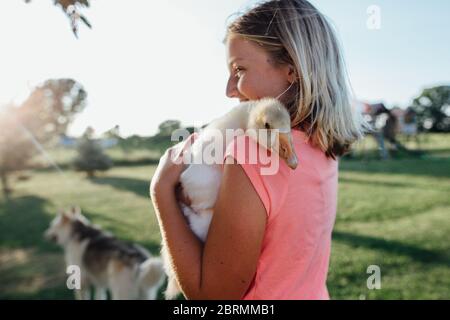 Lächelndes Mädchen hält Enten auf dem Bauernhof Stockfoto