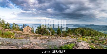 Breites Panorama mit öffentlichen touristischen Rasthaus vor Blick auf wilde skandinavische Berge mit Kiefernwald, das Dorf und zwei Meeresbuchten, su Stockfoto