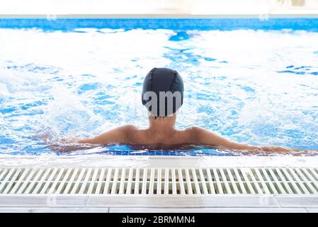 Junger Teenager männlich mit weißen Kappe entspannen in einem Schwimmbad im Spa Stockfoto