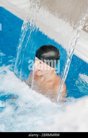 Junge Teenager genießen unter einem Wasserfall Jet in einem Spa Stockfoto