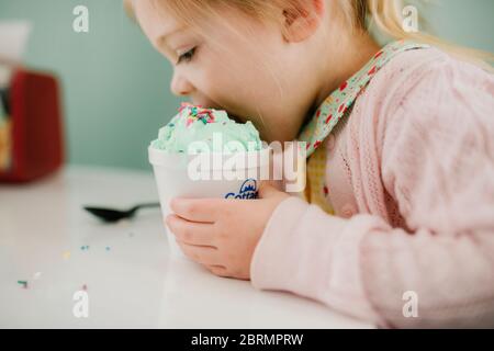 Mädchen, die einen großen Bissen von ihrem grünen Eis Stockfoto