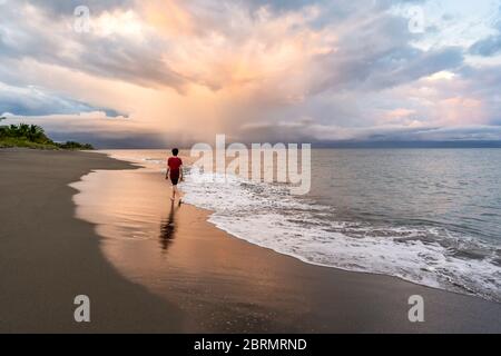 Teenager, die am wunderschönen Strand bei Sonnenuntergang spazieren gehen Stockfoto