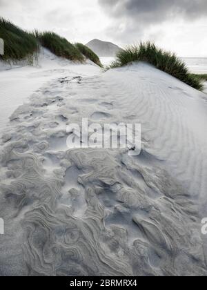 Fußabdrücke auf einer Sanddüne am Windswept Wharariki Beach und den Archway Islands, Puponga, Tasman, Neuseeland Stockfoto