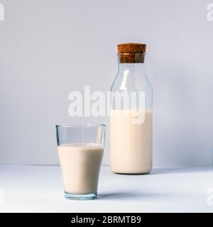 Ein Glas und eine Flasche Milch auf weißem Tisch. Gesundes Essen Konzept. Stockfoto