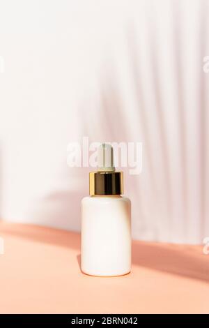 Kosmetische weiße Plastikflasche ohne Marke, tropischer Pflanzenschatten auf weißer Wand als Hintergrund. Natürliche Hautpflegeprodukte Konzept. Stockfoto