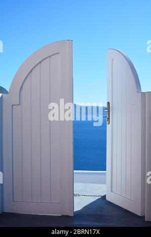 Weiße Holztür, Tor oder Eingang zu einer Villa auf der Insel Satorini im Dorf Oia, Griechenland. Willkommen in einem Ferienresort Stockfoto