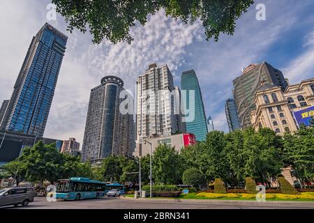 Chongqing, China - Juli 2019 : Öffentliche Busse und Autos fahren auf belebten Straßen der Stadt Chongqing zwischen den modernen Geschäfts-und Geschäftsgebäuden in t Stockfoto