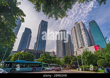 Chongqing, China - Juli 2019 : Öffentliche Busse und Autos fahren auf belebten Straßen der Stadt Chongqing zwischen den modernen Geschäfts-und Geschäftsgebäuden in t Stockfoto