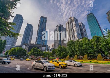 Chongqing, China - Juli 2019: Taxis und Autos fahren auf belebten Straßen der Stadt Chongqing unter den modernen Handels- und Geschäftsgebäuden im Jief Stockfoto