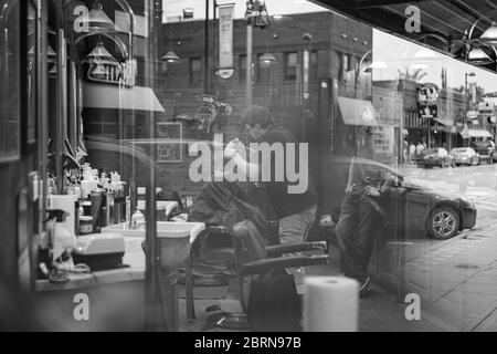 Manhattan, Kansas, USA. Mai 2020. DYLAN ROBERTS, Mitte, schneidet CALDER WEDDLE'S, 4, Haare am Mittwoch. Der Campus Barbershop in Aggieville, Kansas ältestem Einkaufsviertel, ist seit März 17 geschlossen und hat zwei Tage geöffnet. Mai 18 war der erste Tag der Phase 1.5 des Plans, Kansas Wirtschaft wieder zu öffnen. Kredit: Luke Townsend/ZUMA Wire/Alamy Live News Stockfoto