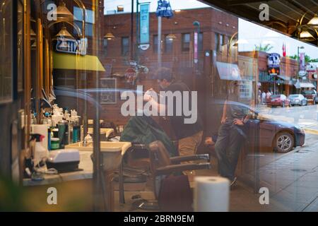 Manhattan, Kansas, USA. Mai 2020. DYLAN ROBERTS, Mitte, schneidet CALDER WEDDLE'S, 4, Haare am Mittwoch. Der Campus Barbershop in Aggieville, Kansas ältestem Einkaufsviertel, ist seit März 17 geschlossen und hat zwei Tage geöffnet. Mai 18 war der erste Tag der Phase 1.5 des Plans, Kansas Wirtschaft wieder zu öffnen. Kredit: Luke Townsend/ZUMA Wire/Alamy Live News Stockfoto