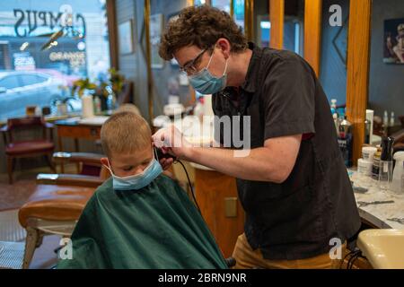 Manhattan, Kansas, USA. Mai 2020. DYLAN ROBERTS, schneidet AM Mittwoch CALDER WEDDLE'S, 4, Haare. Der Campus Barbershop in Aggieville, Kansas ältestem Einkaufsviertel, ist seit März 17 geschlossen und hat zwei Tage geöffnet. Mai 18 war der erste Tag der Phase 1.5 des Plans, Kansas Wirtschaft wieder zu öffnen. Kredit: Luke Townsend/ZUMA Wire/Alamy Live News Stockfoto