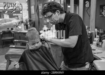 Manhattan, Kansas, USA. Mai 2020. DYLAN ROBERTS, schneidet AM Mittwoch CALDER WEDDLE'S, 4, Haare. Der Campus Barbershop in Aggieville, Kansas ältestem Einkaufsviertel, ist seit März 17 geschlossen und hat zwei Tage geöffnet. Mai 18 war der erste Tag der Phase 1.5 des Plans, Kansas Wirtschaft wieder zu öffnen. Kredit: Luke Townsend/ZUMA Wire/Alamy Live News Stockfoto