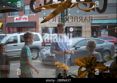 Manhattan, Kansas, USA. Mai 2020. Die Familie Weddle wartet am Mittwoch vor dem Campus Barbershop auf den Haarschnitt. Der Campus Barbershop in Aggieville, Kansas ältestem Einkaufsviertel, ist seit März 17 geschlossen und hat zwei Tage geöffnet. Mai 18 war der erste Tag der Phase 1.5 des Plans, Kansas Wirtschaft wieder zu öffnen. Kredit: Luke Townsend/ZUMA Wire/Alamy Live News Stockfoto