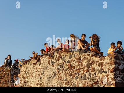 Oia, Santorini, Griechenland - 22. Juli 2014: Touristen warten auf Sonnenuntergang sitzen auf einer Mauer am Aussichtspunkt auf der Burg Stockfoto