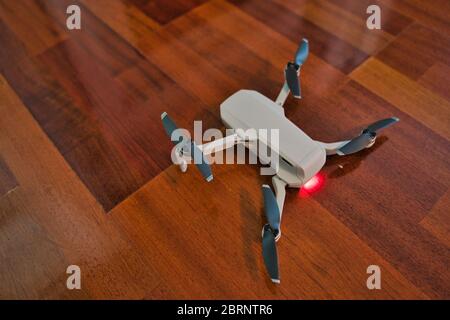 Drohne sitzt auf Holzboden mit Licht auf Anzeige leere Batterie. Drohnenflug im Innenbereich. Stockfoto