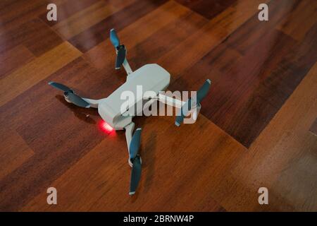 Drohne sitzt auf Holzboden mit Licht auf Anzeige leere Batterie. Drohnenflug im Innenbereich. Stockfoto