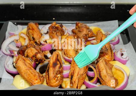 Rohes Hühnerflügel mit Zwiebeln und Kartoffeln einölen Stockfoto