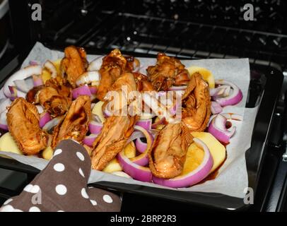 Rohes Hühnerflügel mit Zwiebeln und Kartoffeln in einen Ofen geben Stockfoto