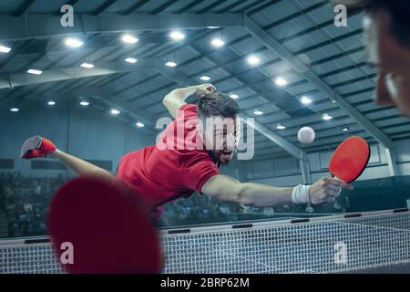 Die Tischtennis Spieler in Bewegung. Fit sport Mann Tennis-Spieler im Spiel auf Sport Arena Hintergrund mit Beleuchtung. Bewegung, Sport, Spiel, stobe conce Stockfoto