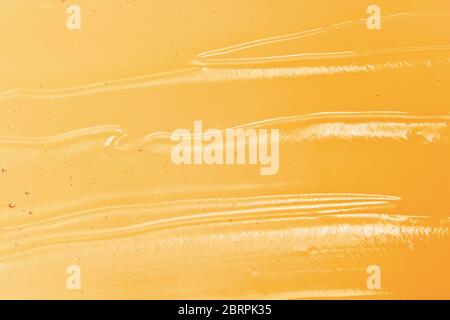 Orangefarbene Geltextur. Kosmetische klare flüssige Creme wischende. Transparente Hautpflege Produkt Probe Nahaufnahme. Farbiger Gelhintergrund Stockfoto
