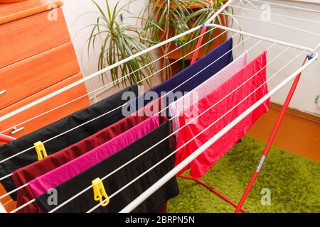 Trocknen von Kleidung auf einem mobilen Trockner. Farbige Bettwäsche auf dem Trockner in der Wohnung. Stockfoto