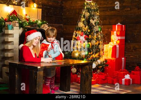 Bruder und Schwester feiern Weihnachten. Kinder in Santa hat schreiben Wunschliste an Santa. Lieber Weihnachtsmann Stockfoto