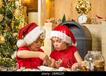 Nette Kinder in santa Hüte Vorbereitung Urlaub Abendessen für die Familie. Santa Cook. Cookie am Heiligabend als Dankeschön Santa Geschenk für das Verlassen Geschenke zu einer Gra Stockfoto