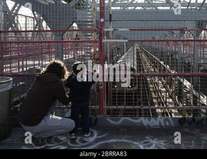 Williamsburg, Usa. Mai 2020. Ein Mann und ein Junge beobachten, wie ein U-Bahn-Auto am Donnerstag, den 21. Mai 2020, über die Williamsburg Bridge in New York City kommt. Die Todesrate des US-Coronavirus liegt jetzt über 90,000 und die Zahl der gemeldeten Fälle übersteigt 1.5 Millionen. Foto von John Angelillo/UPI Quelle: UPI/Alamy Live News Stockfoto