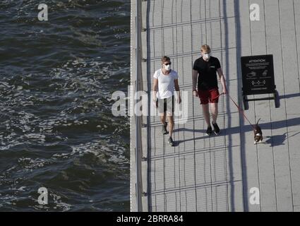 Williamsburg, Usa. Mai 2020. Zwei Männer mit Schutzmaske gehen am Donnerstag, den 21. Mai 2020, mit einem Hund im Domino Park in New York City spazieren. Die Todesrate des US-Coronavirus liegt jetzt über 90,000 und die Zahl der gemeldeten Fälle übersteigt 1.5 Millionen. Foto von John Angelillo/UPI Quelle: UPI/Alamy Live News Stockfoto