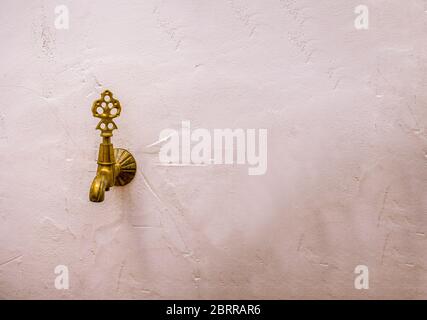 Antike Bronze Wasserhahn an einer weißen Wand. Stockfoto