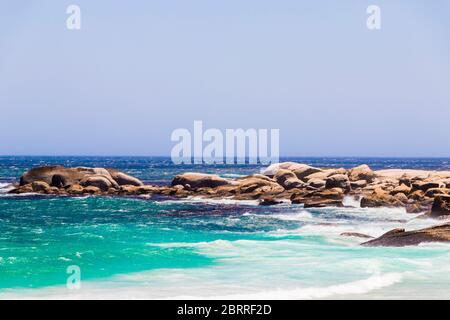 Camps Bay Beach türkisfarbenes Wasser weißer Sand und Felsen in Kapstadt, Südafrika. Stockfoto