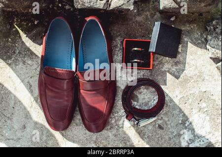 Herrenschuhe, Gürtel und Eheringe von Cherry in einer Schachtel. Accessoires des Bräutigams am Hochzeitstag Stockfoto