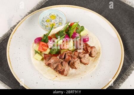 Lammschisch-Kebab in einem josper-Ofen gekocht. Serviert auf einem Teller mit Pita Brot, Gemüse und Sauce. Stockfoto