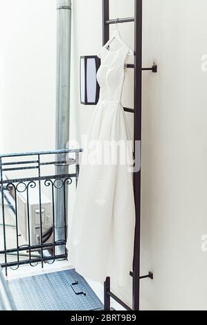 Wunderschöne weiße Hochzeitskleid auf einer Feuerleiter auf dem Balkon. Braut Accessoires in einem Hochzeitstag Stockfoto