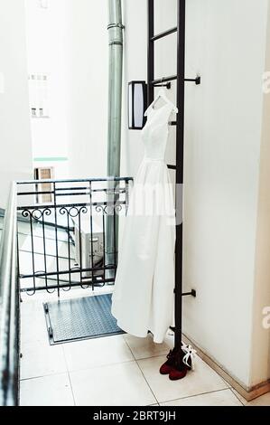 Wunderschöne weiße Hochzeitskleid auf einer Feuerleiter auf dem Balkon. Braut Accessoires in einem Hochzeitstag Stockfoto