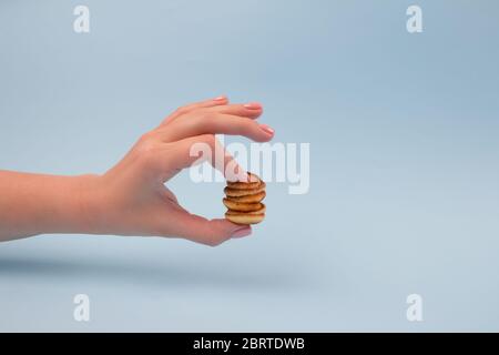 Frau Hand mit perfekter Maniküre hält Mini Baby Pfannkuchen Müsli mit Erdbeeren auf hellblauem Hintergrund mit Kopierraum für Ihren Text und Mock Stockfoto