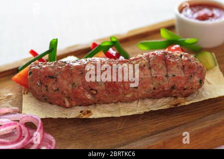 Oktoberfest. Verschiedene gegrillte Würstchen auf einem Holztisch. Gebratene Würstchen auf einer gusseisernen Pfanne. Traditionelle deutsche Street Food, ein Snack Stockfoto