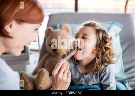 Ärztin untersucht kleine Mädchen im Bett im Krankenhaus. Stockfoto
